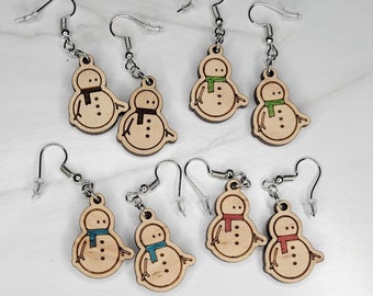 May include: Six pairs of wooden snowman earrings with different colored scarves. The earrings are made of wood and have a silver hook.