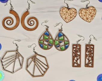 May include: Assortment of wooden earrings in various geometric shapes and designs. Some earrings feature a blue and green mosaic pattern.