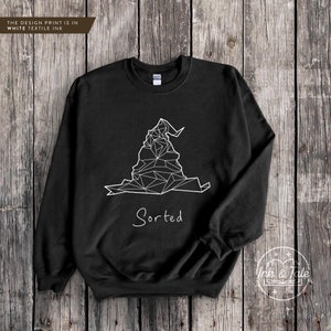May include: Black sweatshirt with a white geometric design of the Sorting Hat from Harry Potter and the text "Sorted" underneath.