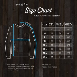 May include: Size chart for an adult crewneck sweatshirt. The chart shows the width, length, and sleeve length in inches for sizes S through 5XL. The chart is on a woodgrain background.
