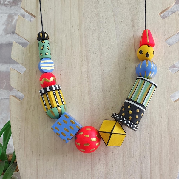 May include: A colorful necklace made of wooden beads with geometric patterns and bright colors, including yellow, red, blue, green, and black.