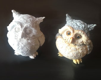May include: Two owl figurines, one white and one with brown and gray feathers. Both owls have large, round eyes.