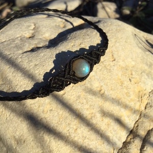 May include: A black cord necklace with a single blue labradorite gemstone bead.
