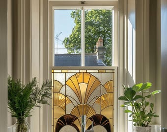 Può includere: Una finestra in vetro colorato con un design geometrico in tonalità oro, marrone e bianco. La finestra è incorniciata in bianco e si affaccia su un albero verde.