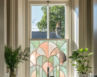 May include: A stained glass window film with a geometric design in shades of green, pink, and brown. The film is installed in a window with a view of a tree and a roof.