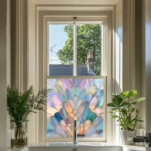May include: A stained glass window film featuring a colourful peacock feather design. The film is fitted to a window in a bathroom with a white sink and tap.