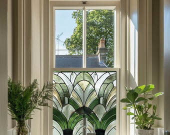 May include: A bathroom window with a stained glass panel featuring a geometric design of green and gold leaves. The window is framed in white and has a view of a tree and a roof.