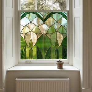 May include: A window with a stained glass design featuring green and white geometric shapes. The window is framed in white and has a white windowsill. A small potted plant sits on the windowsill.