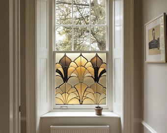 May include: A window with a stained glass design featuring a geometric pattern of gold and black leaves. The window is framed in white and has a white windowsill. A small potted plant sits on the windowsill.
