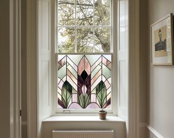May include: A window with a stained glass design featuring geometric shapes in shades of green, purple, and pink. The window is framed in white and has a white windowsill. A small potted plant sits on the windowsill.