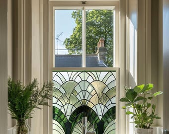 May include: A window with a stained glass design featuring a fan-shaped pattern in shades of green, white, and clear glass. The window is set in a white frame, with a view of trees and a house visible through the glass.
