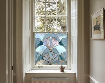 May include: A window with a stained glass design featuring a blue, white and pink geometric pattern. The window is framed in white and has a white windowsill. A small potted plant sits on the windowsill.
