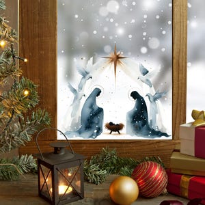 Könnte beinhalten: Weihnachtsszene mit einer Aquarell-Krippe im Fenster, einem beleuchteten Weihnachtsbaum, einer Laterne, Ornamenten und verpackten Geschenken. Die Krippe zeigt Maria, Josef, das Jesuskind und Tauben. Die Geschenke sind in Gold, Rot und Weiß verpackt.