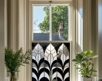 May include: A bathroom window with a stained glass panel featuring a geometric design of black, white, and gray leaves. The window is framed in white and the glass panel is set in a black frame.