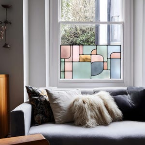 May include: A window film featuring a geometric stained glass pattern with rectangular and rounded shapes in soft shades of pink, sage green, blue, and gold. The design is composed of various sized panels separated by thin black lines.