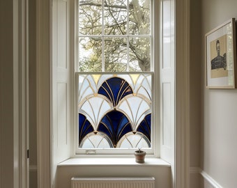 May include: A window with a decorative film featuring a fan-shaped design in white, navy blue, and gold. The window is set in a white frame, with a small potted plant on the sill. The room has light gray walls and a framed picture.