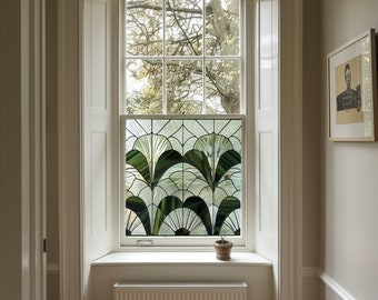 May include: A white window with a stained glass panel featuring a geometric design of green and white leaves. The window is framed by white trim and is set in a white wall. A small potted plant sits on the windowsill.