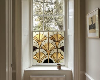 May include: A window with a stained glass design featuring a geometric pattern of gold and black fans. The window is set in a white frame and is surrounded by white trim.
