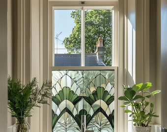 May include: A stained glass window film with a geometric design featuring green and white leaves. The film is installed in a white window frame with a view of a tree and a house in the background.