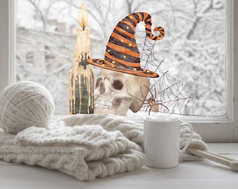 Puede incluir: Naturaleza muerta de Halloween con una calavera con sombrero de bruja, una vela encendida, una araña y una telaraña. Una madeja de lana, una manta de punto y una taza de café completan la escena. Un paisaje nevado se ve a través de la ventana.