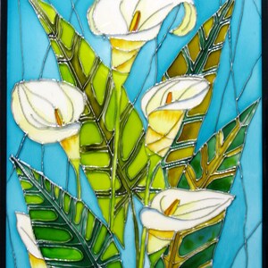 May include: A stained glass artwork featuring white calla lilies with green leaves on a blue background. The artwork is signed "T.S. 2013" in the bottom right corner.