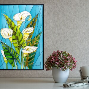 May include: A framed stained glass artwork depicting white calla lilies with green leaves on a blue background. The artwork is signed "Y.G. 2013".