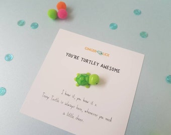 May include: A white card with the text "You're Turtley Awesome" and a small green turtle figurine. The card also includes the text "I know it, you know it x Teeny Turtle is always here, whenever you need a little cheer."