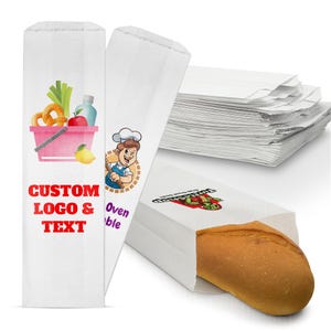 May include: White paper sandwich bags with custom logo and text. One bag features a cartoon chef and a pink basket with food items. Another bag holds a loaf of bread. A stack of blank bags is in the background.
