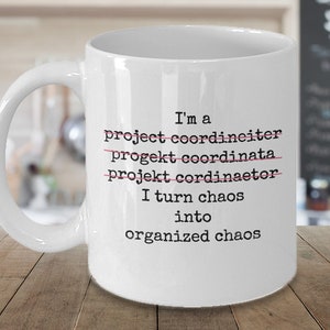 May include: White ceramic coffee mug with black text that reads "I'm a project coordinator I turn chaos into organized chaos". The words "project coordinator" are crossed out with a red line.