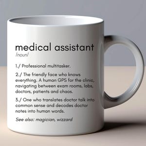 May include: White ceramic mug with a black and white definition of a medical assistant. The definition reads: "Professional multitasker. The friendly face who knows everything. A human GPS for the clinic, navigating between exam rooms, labs, doctors, patients and chaos. One who translates doctor talk into common sense and decodes doctor notes into human words. See also: magician, wizzard"