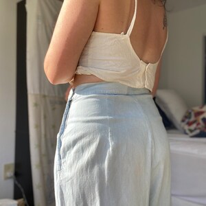 May include: A pair of light blue wide-leg pants with a high waist and a zipper closure. The pants are made of a lightweight fabric and have a relaxed fit.