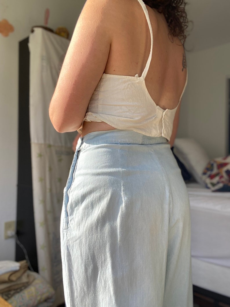 May include: A pair of light blue wide-leg pants with a high waist and a zipper closure. The pants are made of a lightweight fabric and have a relaxed fit.