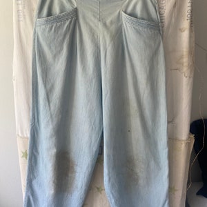 May include: Light blue wide-leg pants with a high waist and two front pockets. The pants have a subtle pinstripe pattern and are made of a lightweight fabric.