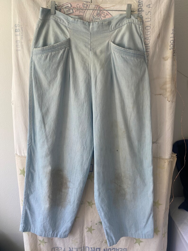May include: Light blue wide-leg pants with a high waist and two front pockets. The pants have a subtle pinstripe pattern and are made of a lightweight fabric.