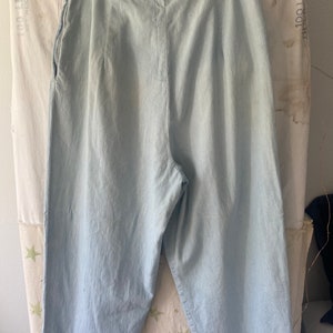 May include: Light blue denim wide-leg cropped pants with a zipper fly and a button closure.