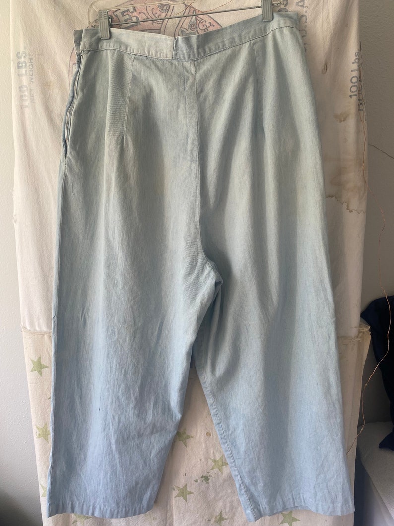 May include: Light blue denim wide-leg cropped pants with a zipper fly and a button closure.