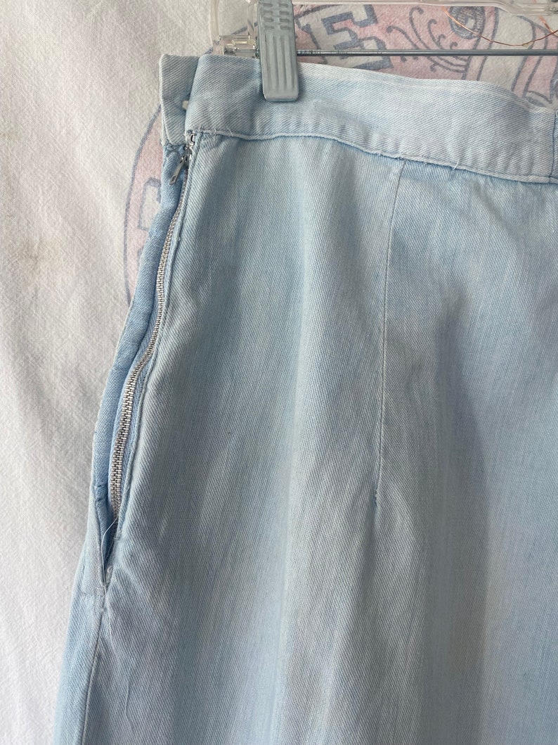 May include: A light blue denim skirt with a zipper on the side.