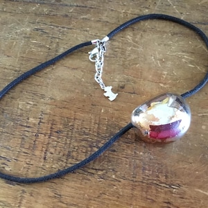 Pode incluir: Um colar de cordão preto com um único pendente metálico grande de tom prateado polido com uma forma arredondada e irregular. O colar inclui um fecho de mosquetão de metal prateado, uma corrente extensora ajustável e um pequeno pendente em forma de cão.