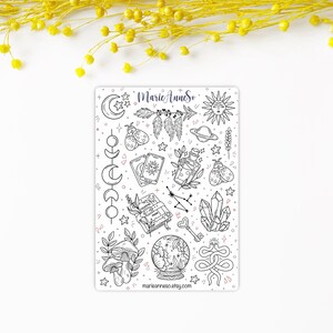 May include: A sheet of black and white stickers with a variety of mystical and witchy themed illustrations. The stickers include a crescent moon, a sun, a crystal, a snake, a mushroom, a book, a key, a bottle, a feather, a tarot card, a planet, a constellation, and a crystal ball. The stickers are on a white background and have a pink and blue color scheme. The text "MarieAnneSo" and "marianneeso.etsy.com" are included on the sheet.