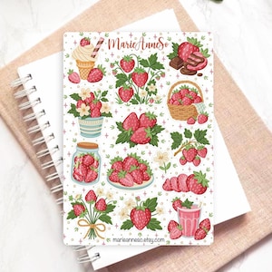 May include: A white notebook with a strawberry-themed design. The design includes illustrations of strawberries, ice cream, chocolate, and a strawberry smoothie. The text "MarieAnneSo" and "marieanneso.etsy.com" are also visible.