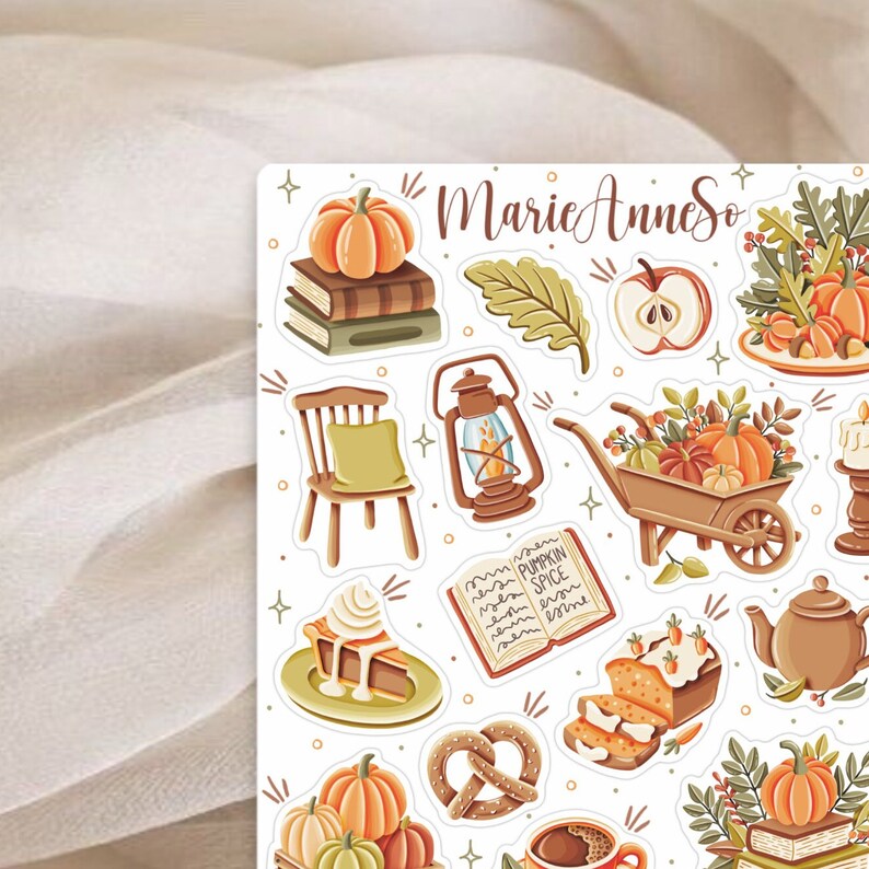 K&ouml;nnte beinhalten: Ein Set mit Herbst-Stickern mit K&uuml;rbissen, einer Laterne, einer Schubkarre, einem Buch, einem Kuchen, einem Brezel, einer Kaffeetasse und einer Teekanne. Die Sticker sind auf wei&szlig;em Hintergrund und haben ein verspieltes, herbstliches Flair.