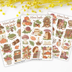 Peut inclure: Trois planches d'autocollants avec des illustrations sur le thème de l'automne. Chaque planche présente divers éléments d'automne comme des citrouilles, des champignons, des glands, des hérissons, des livres et des tasses. Le texte "MarieAnneso.etsy.com" est visible.