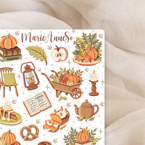 K&ouml;nnte beinhalten: Ein Set mit Herbst-Stickern mit verschiedenen Motiven, darunter K&uuml;rbisse, Bl&auml;tter, eine Schubkarre, eine Teekanne, ein Buch, eine Laterne, ein Kuchen, ein Brezel und ein Apfel. Die Sticker sind auf wei&szlig;em Hintergrund und haben einen Vintage-Look.