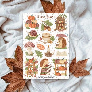 Peut inclure: Une planche d'autocollants avec des illustrations sur le thème de l'automne. Les motifs comprennent des citrouilles, un escargot, un champignon, un hérisson lisant, une tasse de café et un arbre avec des livres. Le texte "MarieAnneSo" et "marieanneso.etsy.com" sont également visibles.