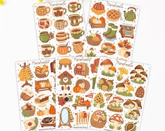 Peut inclure: Cinq planches d'autocollants illustrant des motifs automnaux tels que des tasses, des citrouilles, des champignons, des glands, des tricots et des objets domestiques. Chaque planche porte le texte MarieAnneSo et présente des icônes saisonnières.