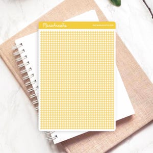 May include: A sheet of stickers with a yellow and white gingham pattern. The stickers are rectangular and have rounded corners. The text "MarieAnneSo" is printed in yellow on the top of the sticker sheet. The stickers are on top of a spiral notebook and a tan journal.