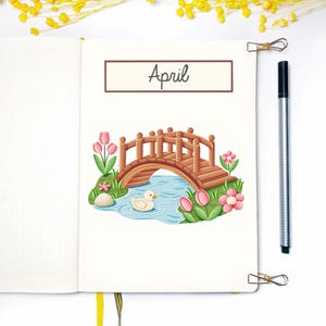 Pu&ograve; includere: Una pagina bianca con la parola "Aprile" scritta in marrone in alto. Un'illustrazione di un ponte di legno su uno stagno blu con un'anatra bianca che nuota nell'acqua. Fiori rosa e foglie verdi circondano lo stagno.