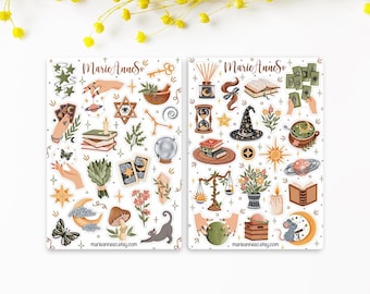 May include: Two sticker sheets labelled MarieAnneSo featuring various illustrations including hands, tarot cards, crystals, a crystal ball, a witch hat, books, a cat, a mouse, plants, stars, moons, and celestial elements in earthy tones and gold accents.