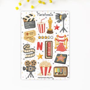 Peut inclure: Une planche d'autocollants avec des illustrations sur le thème du cinéma. Comprend un clap de cinéma, du pop-corn, une bobine de film, des billets, une statuette Oscar, un projecteur et une télévision vintage. Le mot "CINEMA" est affiché en style chapiteau. Le nom de la boutique est "MarieAnneSo".