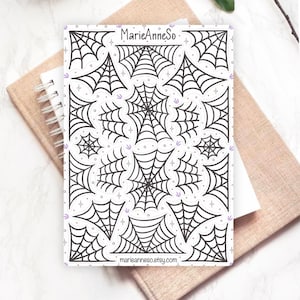 Peut inclure: Une planche d'autocollants rectangulaire présentant diverses illustrations de toiles d'araignées noires sur fond blanc. La feuille inclut le texte MarieAnneSo en haut et marieanneso.etsy.com en bas, agrémenté de petites étoiles violettes.
